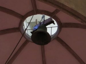 A bell being lowered through the roof of the nave